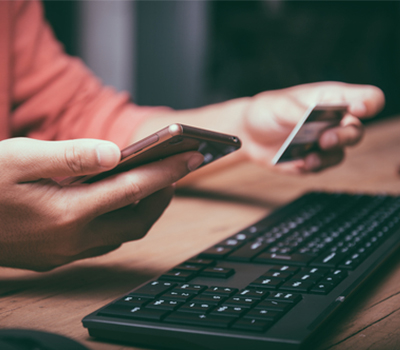 Man using smartphone, credit card and computer keyboard